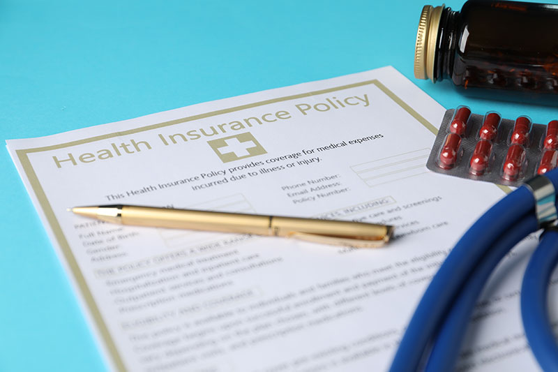 health-insurance-policy-pen-and-pills-on-light-blue